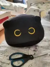 Black cat-shaped pouch with yellow circular eyes.
