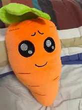 Orange plush carrot with green leafy top and embroidered black eyes.