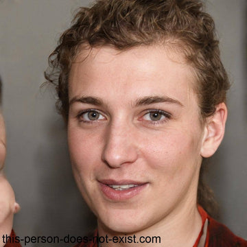A smiling person with light skin, hazel eyes, and curly brown hair.